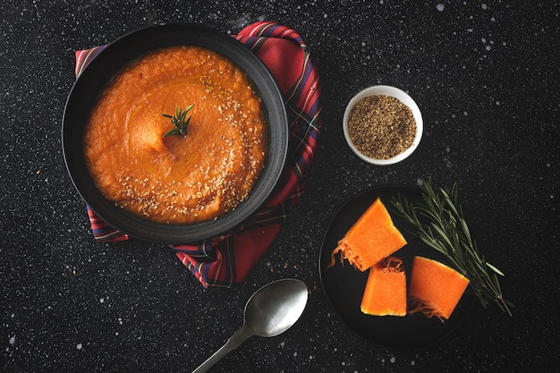 Crema di zucca casalinga e sana con pane dall'alto sul tavolo scuro. lay piatto