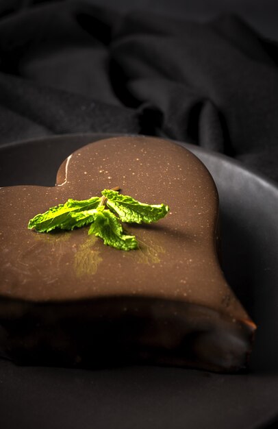 黒の背景に自家製ハート型チョコレートケーキ