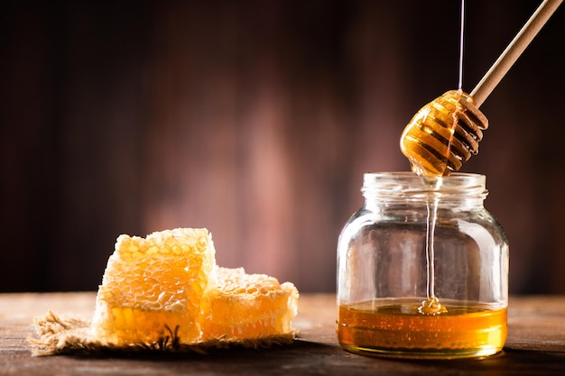 Homemade honey jar with honeycomb on a rustic wooden table close up