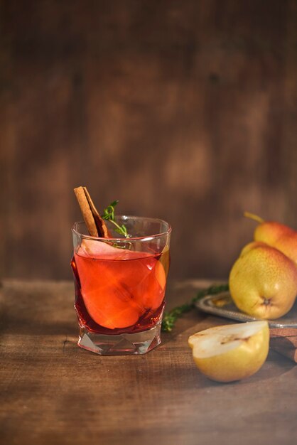 Homemade hot mulled pear cider with a cinnamon stick on a wooden surface