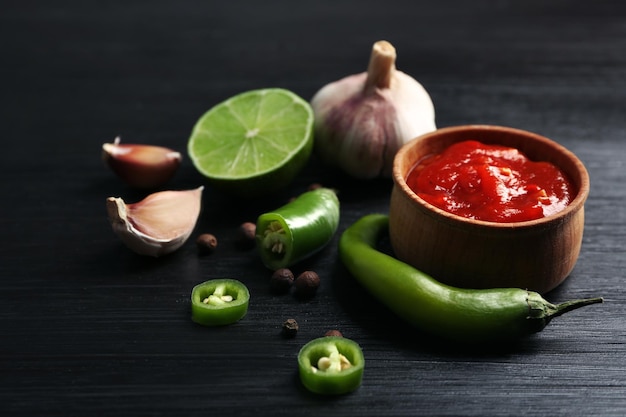 Homemade hot sauce and spices on dark wooden background