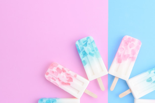 Homemade Ice cream sticks , popsicle , ice pop or freezer pop on blue and pink pastel colors background