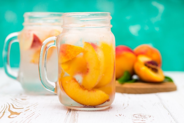 Homemade iced lemonade with ripe peaches. Fresh peach ice tea in a mason jar.