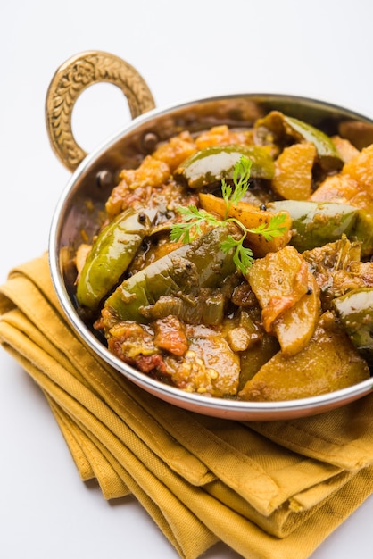 自家製のインドのスパイシーなナスとポテトカレーは、ヒンディー語でaloo Baigan ki sabziとも呼ばれ、カダイまたは白いボウルで提供されます。