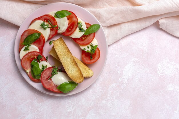 Homemade Italian caprese salad with sliced tomatoes, mozzarella cheese, basil