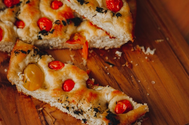 Homemade Italian Focaccia, with tomato and olive oil on a rustic wooden background.