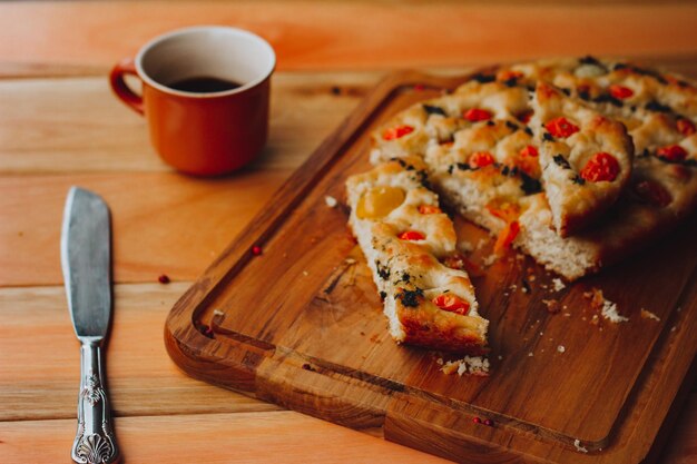 Homemade Italian Focaccia, with tomato and olive oil on a rustic wooden background.