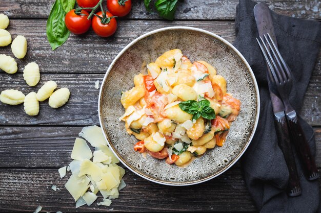 Homemade italian gnocchi with tomato, garlic, basil and mozzarella cheese on wooden table