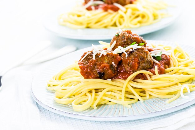 Homemade Italian meatballs garnished with cilantro and parmesan cheese over spaghetti for dinner.