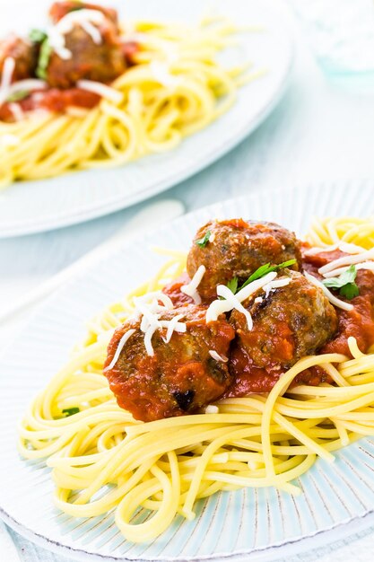 Homemade Italian meatballs garnished with cilantro and parmesan cheese over spaghetti for dinner.