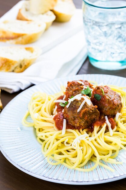 Homemade Italian meatballs garnished with cilantro and parmesan cheese over spaghetti for dinner.