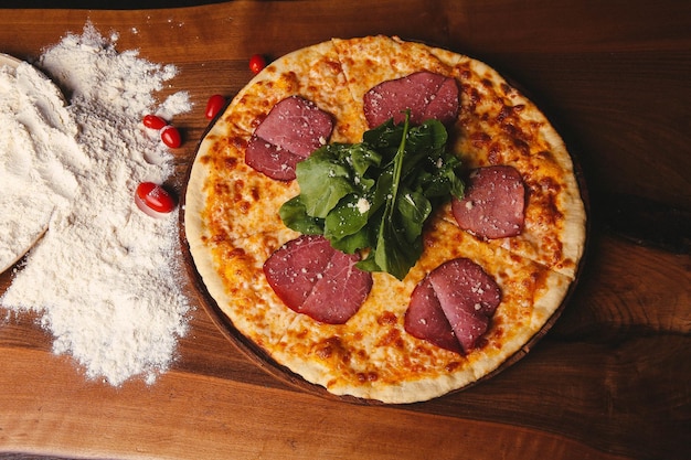 Homemade Italian pizza with mozzarella cheese salami tomato sauce pepper arugula and spices