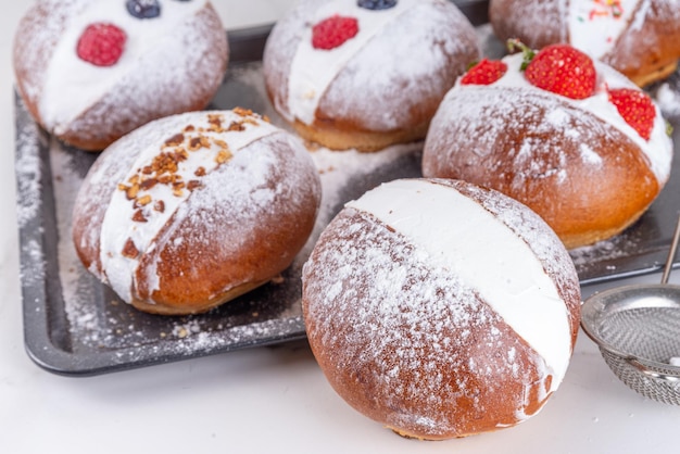 Homemade italian sweet Maritozzi buns breakfast dessert brioche stuffed with whipped cream with various topping nuts fruit