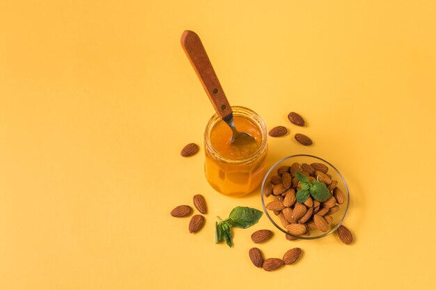 Homemade jam in a glass jar and chestnuts on yellow background.