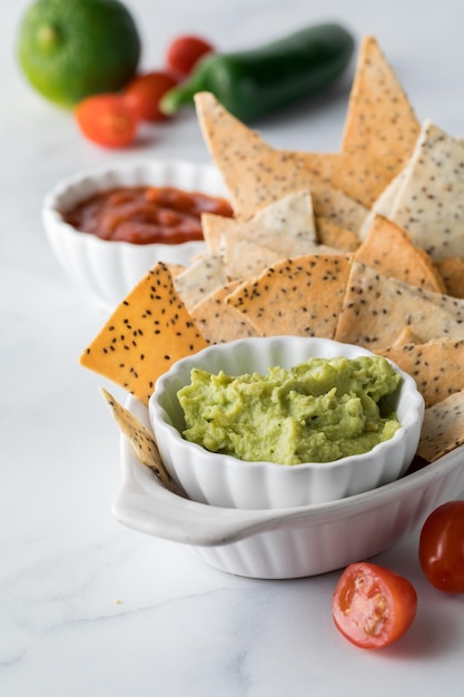 Homemade keto diet tortilla chips in a bowl with guacamole and salsa in behind