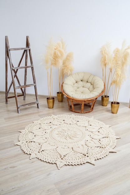 Homemade knitted rug made of thick threads handmade a handmade rug made of beige threads lies in the living room near the armchair the art of knitting