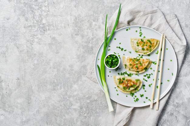 Homemade Korean dumplings, chopsticks, fresh green onions. 