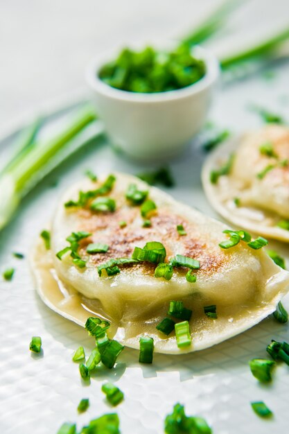 Homemade Korean dumplings, chopsticks, fresh green onions. 