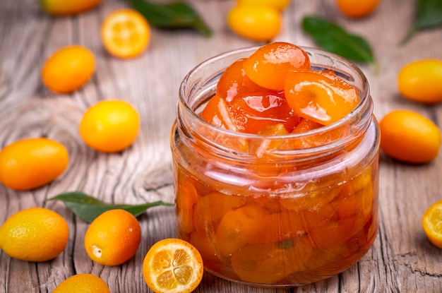 Photo homemade kumquat jam in jar and fresh kumquats top view