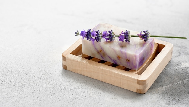 Homemade lavender soap on wooden soap dish on marble table.