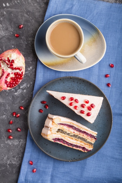 Torta a strati fatta in casa con marmellata di melograno e una tazza di caffè su uno sfondo di cemento nero. vista dall'alto, da vicino.