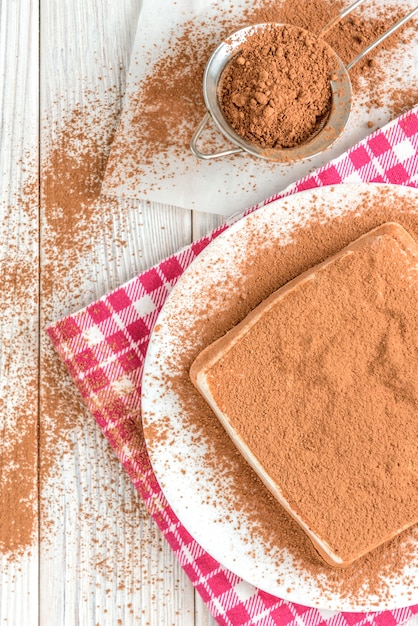 Homemade layered cottage cheese souffle dessert with cocoa on white wooden table