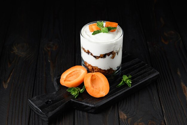 Homemade layered dessert with fresh apricot cream cheese or yogurt granola on rustic background