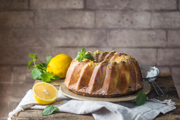 Homemade lemon bundt cake with icing sugar on a black background