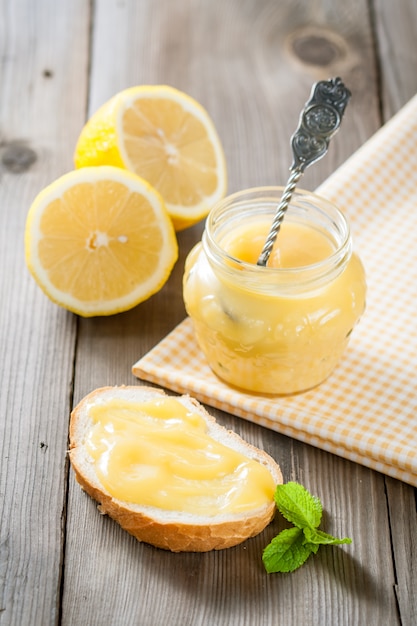 Homemade lemon curd in jars with fresh lemons