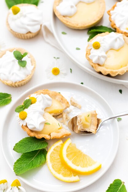 Homemade lemon curd tartlets with meringue and mint leaves