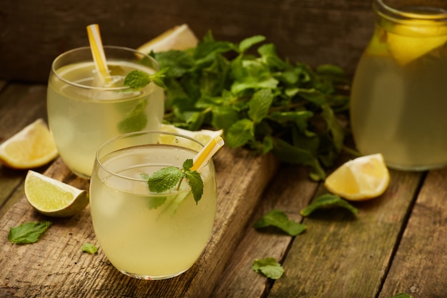 Limonata fatta in casa in due bicchieri con cannucce sul vecchio tavolo di legno