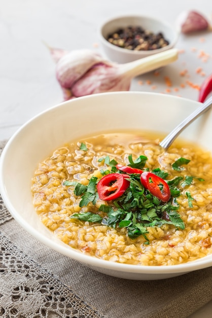 Homemade lentil soup in bowl on light background. Healthy vegetarian food. Selective focus.