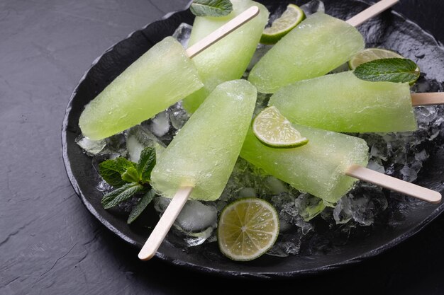 Foto limone e menta fatti in casa impilati su un piatto con il ghiaccio su uno sfondo nero