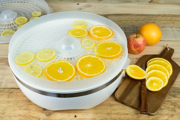 Homemade machine to dehydrate food with orange slices on kitchen table.