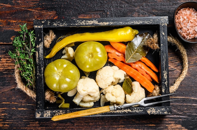 Conserva di verdure marinate e sottaceti fatte in casa su vassoio di legno.