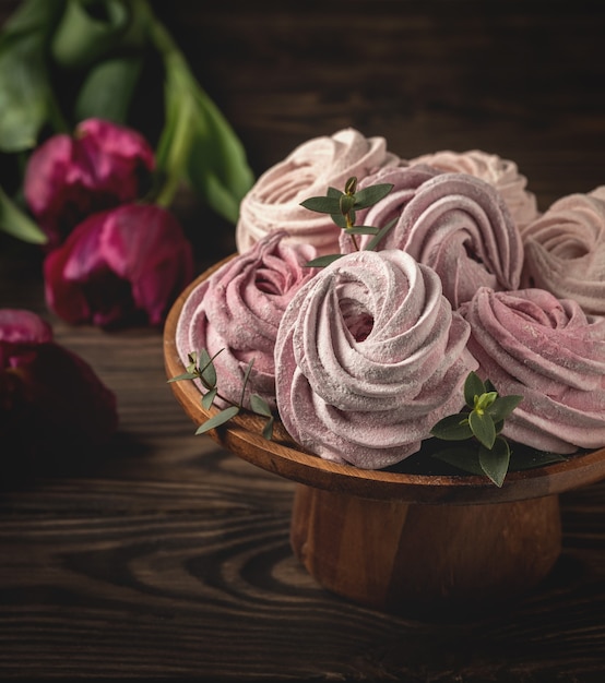 Homemade marshmallows on a stand and flowers tulips on a wooden table