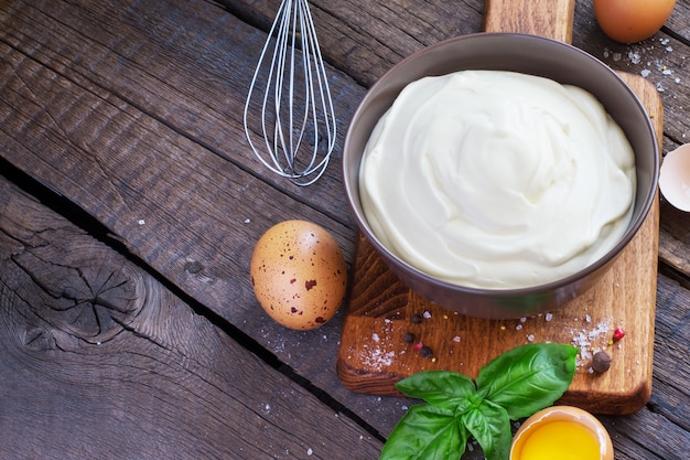 Homemade mayonnaise sauce in a bowl on a wooden table