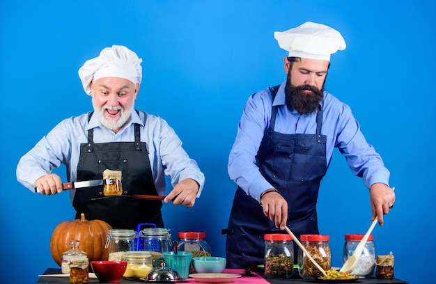 Pasto fatto in casa preparare il cibo ricetta culinaria libro culinario chef uomini che cucinano padre e figlio hobby culinario ristorante di famiglia ingredienti selezionati uomini maturi con la barba cuochi professionisti del ristorante