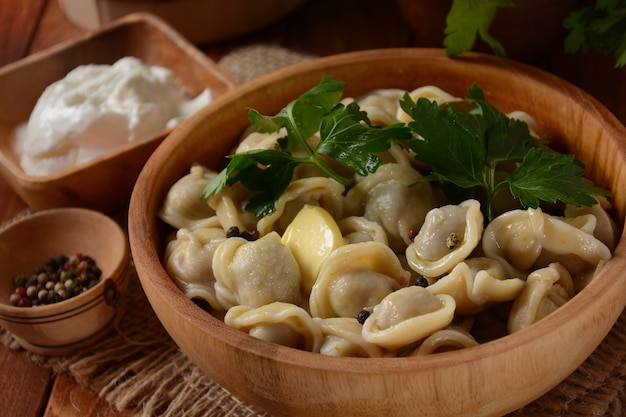 Homemade Meat Dumplings  served with sour cream and  fresh parsley on plate. Traditional Russian food- pelmeni