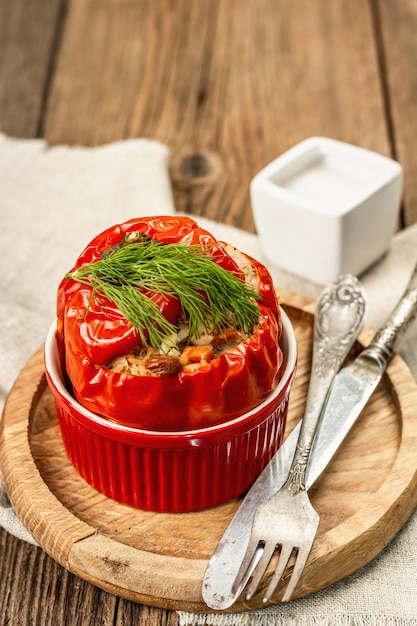 Домашний болгарский перец, фаршированный мясом и рисом. Оливковое масло, соус, столовые приборы. Традиционная здоровая пища, старинный деревянный фон, крупный план, выборочный фокус