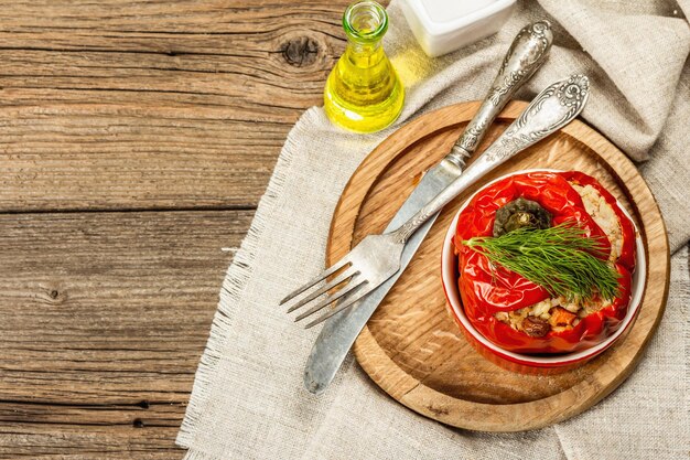 Homemade meat and rice stuffed bell peppers. Olive oil, sauce, cutlery. Traditional healthy food, vintage wooden background, top view