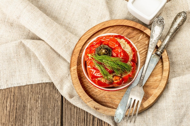 Домашний болгарский перец, фаршированный мясом и рисом. Оливковое масло, соус, столовые приборы. Традиционная здоровая еда, старинный деревянный фон, вид сверху