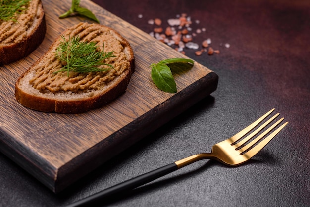 Homemade meat snack liver pate with toast on a dark concrete background