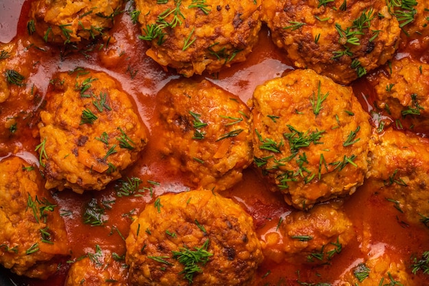 Homemade meatballs in tomato sauce with dill closeup food background