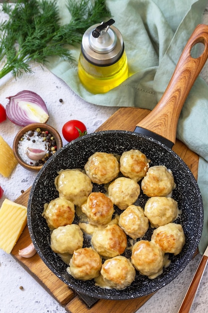 Homemade Meatballs with cheese sauce in a pan on a light stone or slate