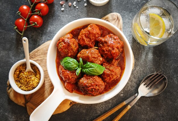 Homemade meatballs with tomato sauce and spices served in white pan on grey background. Top View. Flat lay.