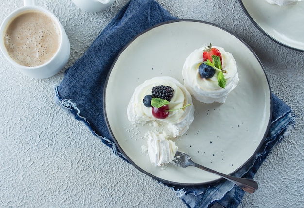 Homemade Meringue dessert Pavlova cake met verse bessen, kopje koffie latte.