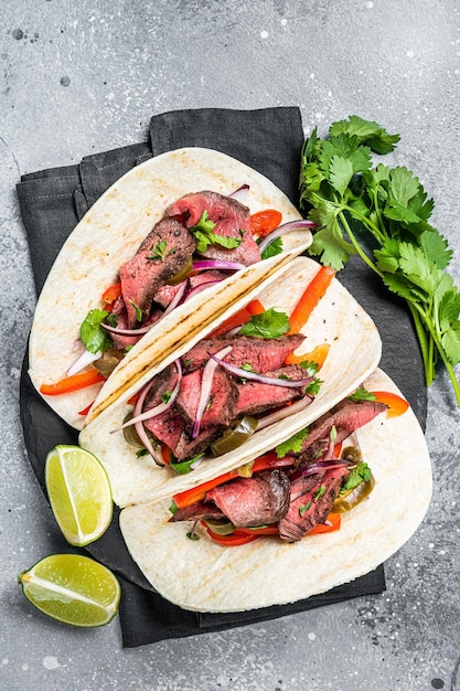 homemade mexican steak steet tacos with cilantro green sauce jalapenos and onion gray background top view