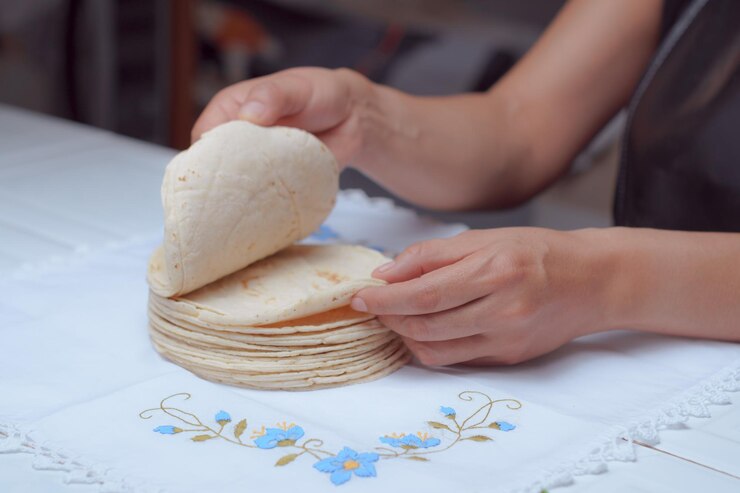 自家製のメキシコのトルティラ 女性の手がトルティラを握っている