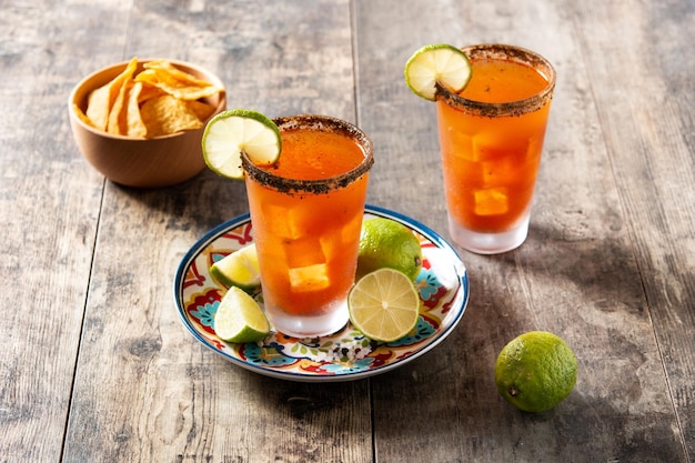 Homemade michelada cocktail with beer lime juicehot saucesalted rim and tomato juice on wooden table